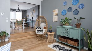 A modern living room with a wicker chair, a teal cabinet, and decorative plates on the wall.