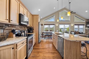 Une cuisine spacieuse dotée de meubles en bois, d’appareils électroménagers en acier inoxydable et d’un grand îlot central.