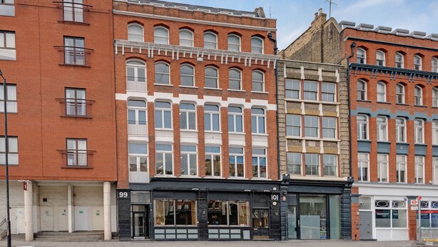 A row of red brick buildings with large windows and a black storefront. - Heinze Building by City Living London (London)