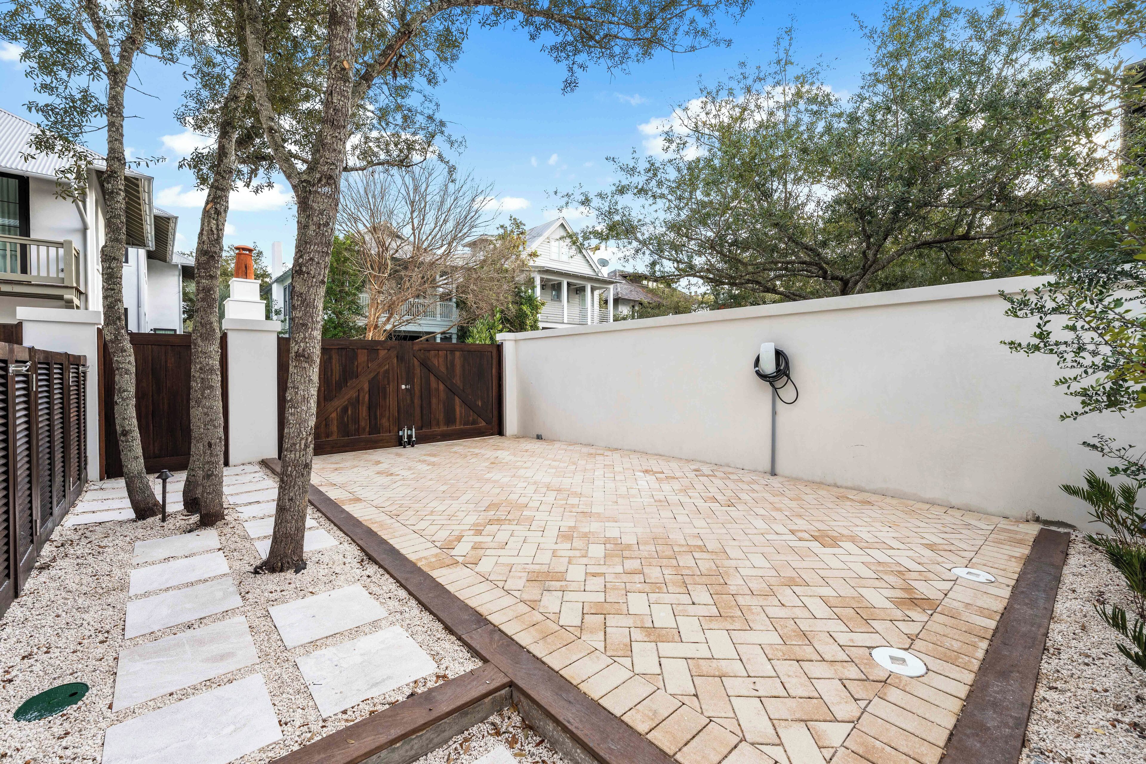 Een bestraat terras met een visgraatmotief, omgeven door een lage witte muur en een houten schutting.