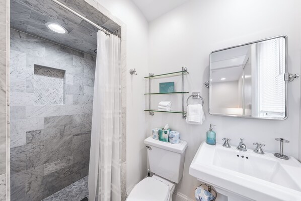 Un baño con ducha, inodoro, lavamanos y espejo.