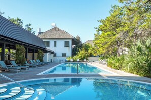 Une piscine avec des chaises longues, un espace abrité et un bâtiment doté d’un toit en pente.