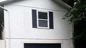 Une maison à deux étages avec un garage et une fenêtre équipée de volets.