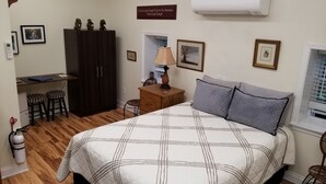 Une chambre à coucher comprenant un lit, un bureau, deux tabourets, une armoire, une lampe et une citation inspirante sur le mur.