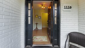 A doorway with a number sign, a wooden floor, and a chair outside.