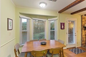 Un comedor con una mesa y sillas de madera, una ventana con persianas y una puerta decorada.