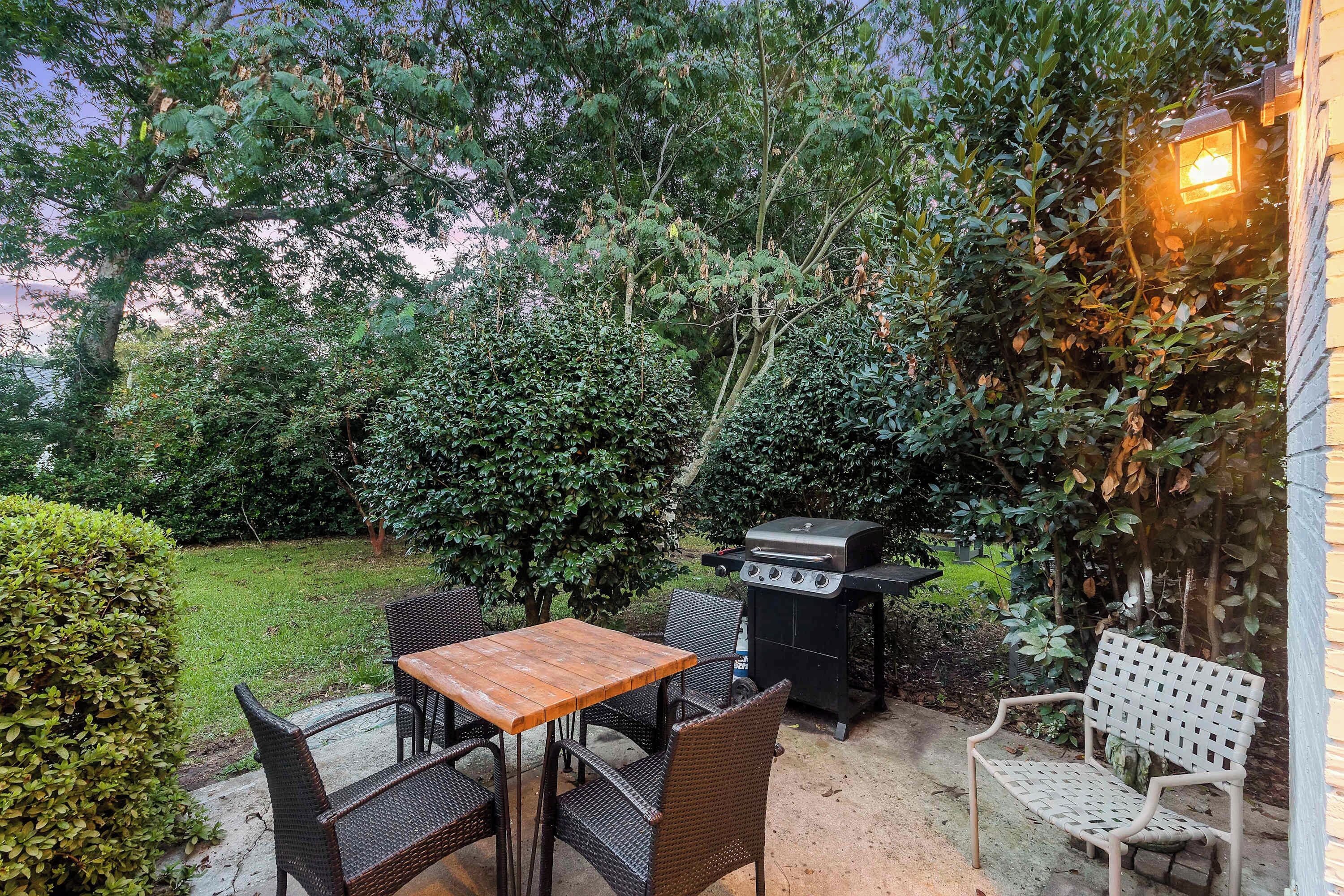 Une terrasse extérieure avec une table et des chaises, un barbecue et un banc.