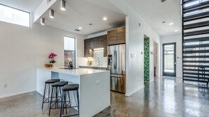 Une cuisine moderne dotée d’un îlot central, de tabourets de bar et d’appareils électroménagers en acier inoxydable.