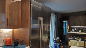 Una cuina moderna amb armaris de fusta, un refrigerador d'acer inoxidable i una zona de menjador amb taula i cadires.