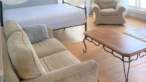Une chambre à coucher avec un lit, une chaise, une table et un ventilateur de plafond.
