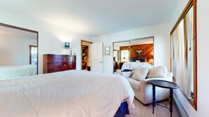 A bedroom with a large bed, a dresser, a sofa, and a small table. - Snowcreek I 28, Light and Bright Corner Condo with Mountain Views and Fireplace by RedAwning (Mammoth Lakes)