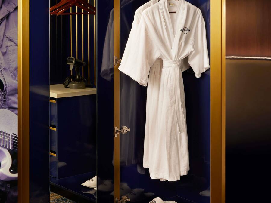 A white robe hanging in a room with a dark blue wall and a gold frame.