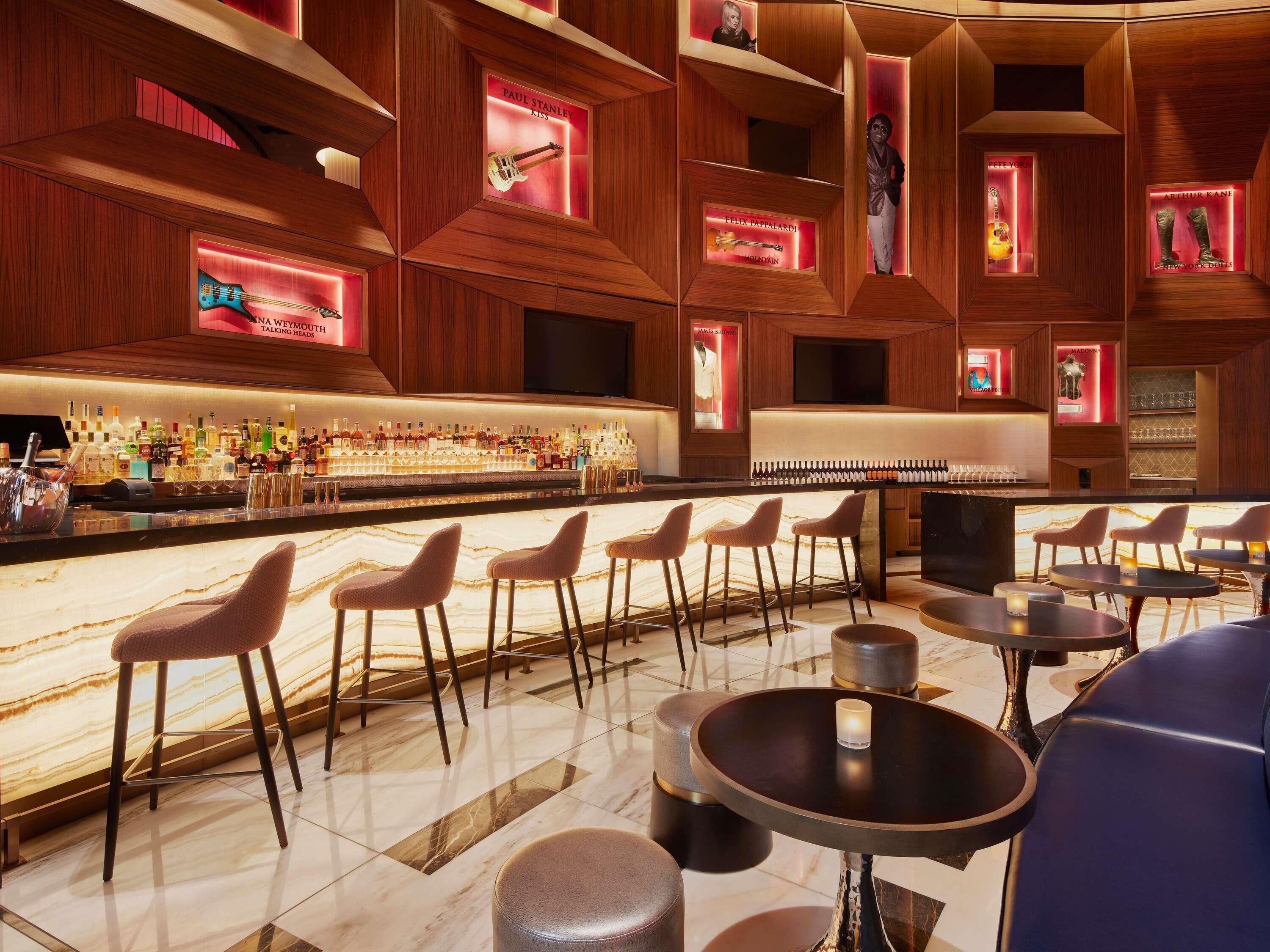 A bar area with a marble countertop, multiple stools, and a variety of bottles.