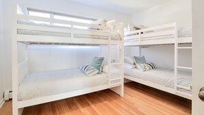 A room with two bunk beds, wooden flooring, and a skylight.