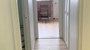 A hallway with a wooden floor leading to a room with a window and a door. - Deluxe Beachfront Villa 3 Bedroom, sleeps 10 (Mar)