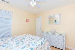 A bedroom with a bed, a dresser, a ceiling fan, a window with blinds, and a wall-mounted mirror. - Beach Break - 4BR Home - 1 Level Living with Covered Porch (Surf City)