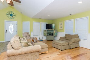 A living room with two beige sofas, a television, and a decorative wall piece. - Beach Break - 4BR Home - 1 Level Living with Covered Porch (Surf City)