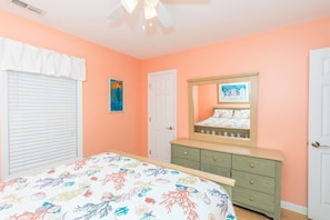 Un dormitorio con cama, cómoda, puerta y ventilador de techo.
