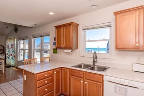 A kitchen with wooden cabinets, a white countertop, a stainless steel sink, and a dishwasher.