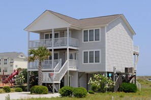 A two-story beachfront house with a balcony, a stairway, and a slide in the yard. - Mermaid Avenue Oceanview 4 Bedroom Home in Surf City – Perfect for the whole (Surf City)