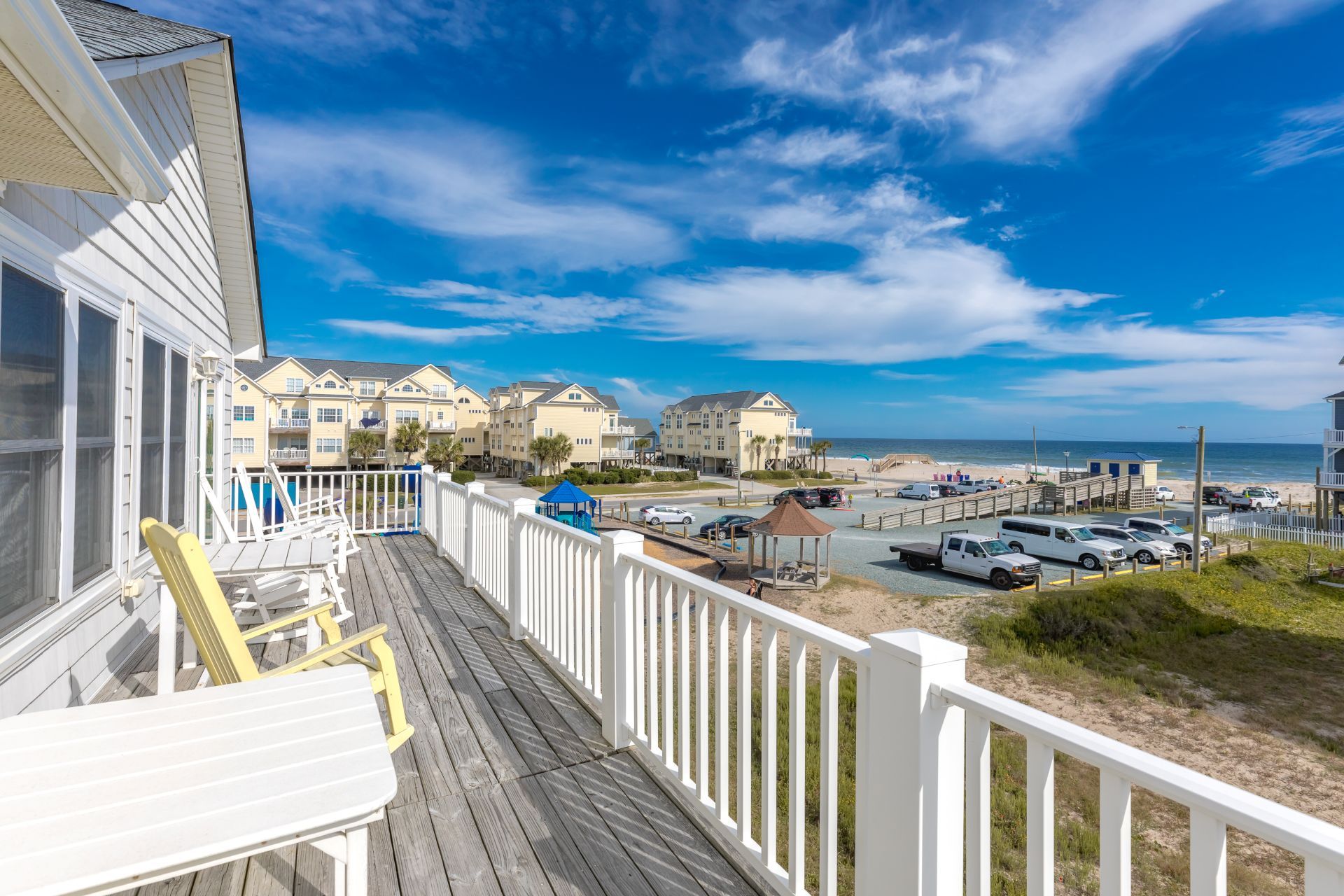 Une propriété située en bord de mer, dotée d’une terrasse en bois, d’un belvédère et offrant une vue sur la plage et l’océan.