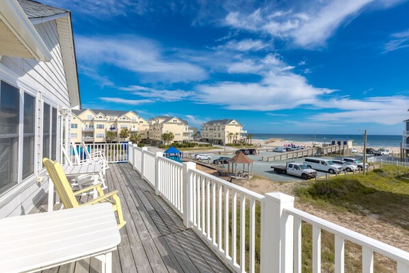 A beachfront property with a wooden deck, a gazebo, and a view of the beach and ocean.