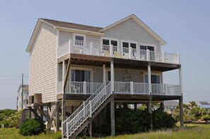 A two-story house with a balcony on the upper floor, a staircase leading to the balcony, and a small porch area.