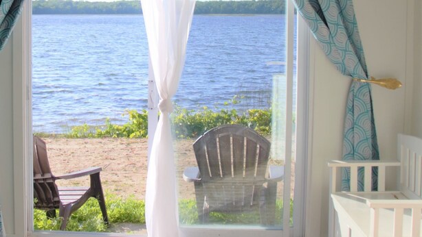 Una habitación con vista a un lago, una silla y una pequeña mesa.