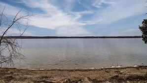 Un lago tranquilo con cielo despejado y una orilla lejana.