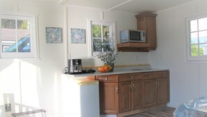 Una cocina con armarios de madera, microondas, cafetera y un florero con flores.
