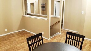 Una habitación con paredes color crema, suelo de madera y una mesa de comedor con dos sillas.