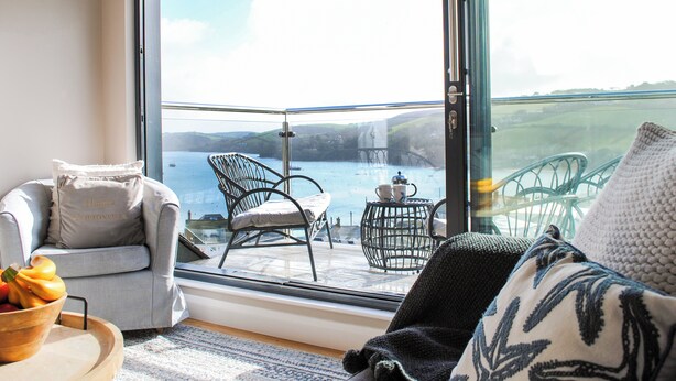 A balcony with a view of the sea, a chair, a table with cups and a teapot, and a bowl of fruit. - Higher Cliftonville (Dorking)