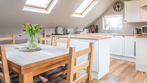 A modern kitchen with skylights, wooden furniture, and white cabinetry. - Higher Cliftonville (Dorking)