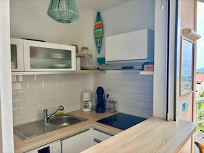 Una cocina compacta con un lavamanos, una cafetera y un microondas.