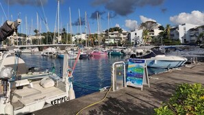 A marina with multiple boats docked, a signboard with information, and buildings in the background. - Martinique!  Beautiful, fully renovated studio with sea view (ANSE MITAN - LES 3 ILETS)