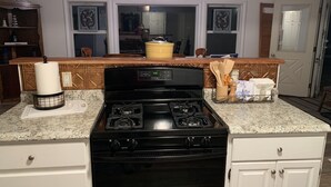 Una cucina con un piano cottura nero, mobili bianchi e un ripiano in granito.