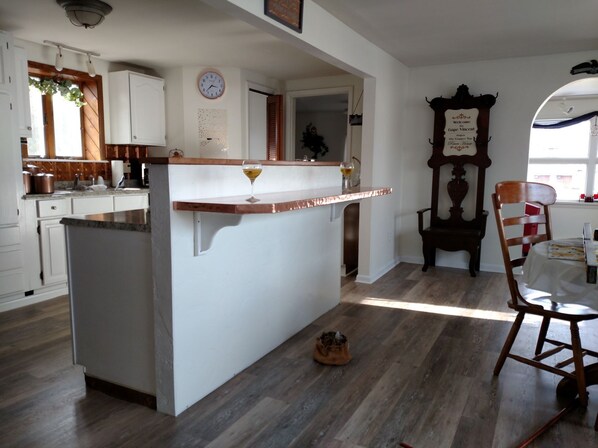 A kitchen with a central island, wooden cabinets, a clock, and a rustic chair.