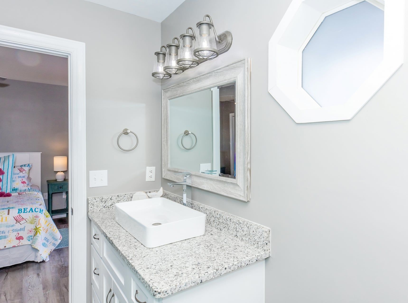 A bathroom with a white sink, a large mirror, and a towel ring on the wall.