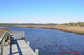 A wooden pier extending into a calm body of water with a clear sky above.