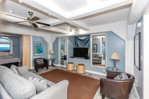 A living room with a ceiling fan, a television, a sofa, a chair, and a coffee table.