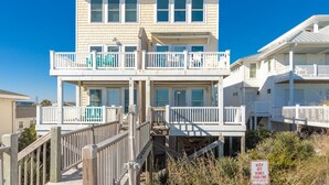 A multi-story beachfront building with balconies, a wooden deck, and a sign indicating a $500 fine for disturbing dunes. - Vitamin Sea - Oceanfront, 5 BR Home in Surf City - Elevator! (Surf City)