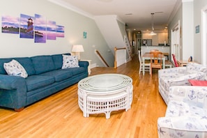 A living room with a blue sofa, a white wicker coffee table, and a patterned sofa. - Vitamin Sea - Oceanfront, 5 BR Home in Surf City - Elevator! (Surf City)