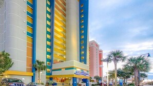 Ein mehrstöckiges Hotel mit markanter vertikaler Gestaltung, das gelbe, blaue und weiße Farbtöne kombiniert.