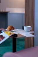 Una mesa con un croissant, una taza blanca y un menú.