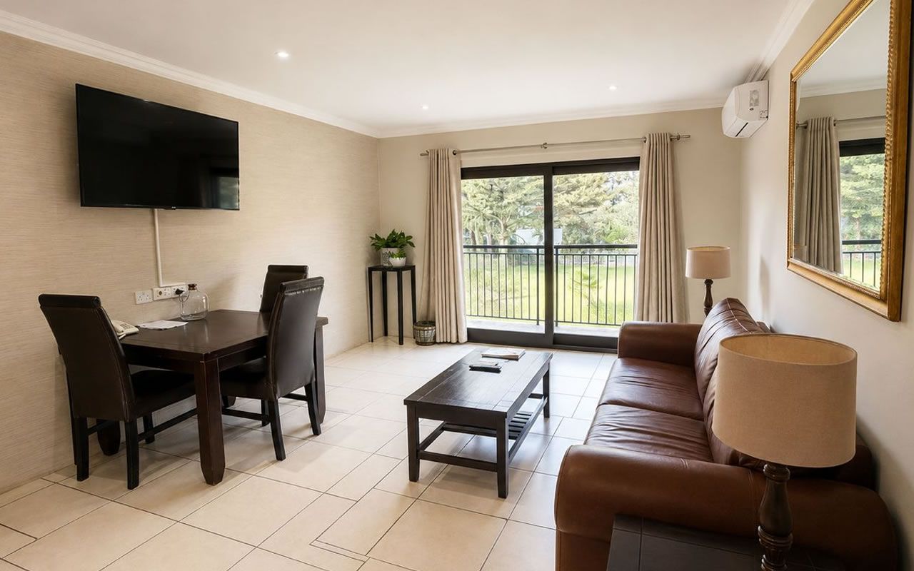 A living room with a TV, a sofa, a coffee table, and a dining area with chairs.