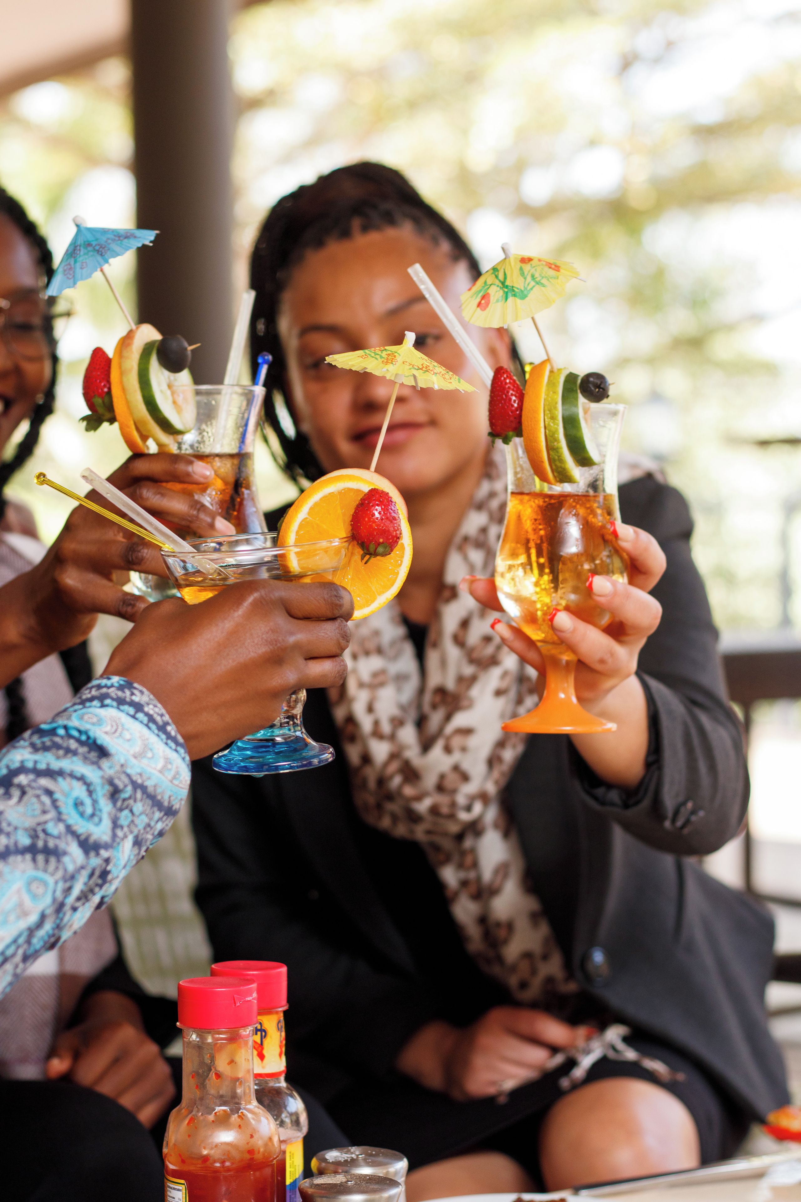 A group of people toasting with drinks that have fruit garnishes and straws.