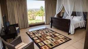 A hotel room with a bed, a TV, a desk, and a view of the outdoors. - The Royal Solwezi Hotel (Solwezi)