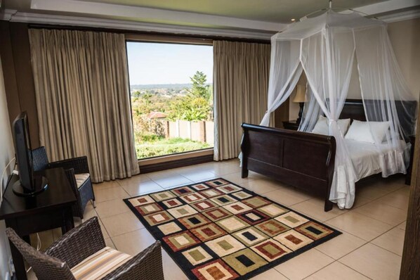 A hotel room with a bed, a TV, a desk, and a view of the outdoors. - The Royal Solwezi Hotel (Solwezi)