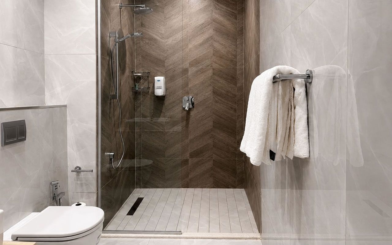 Une salle de bain moderne équipée d’une douche, de toilettes et d’un porte-serviettes.