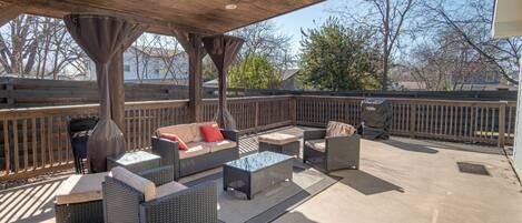An outdoor patio with wicker furniture, a ceiling fan, and a view of the surrounding area.